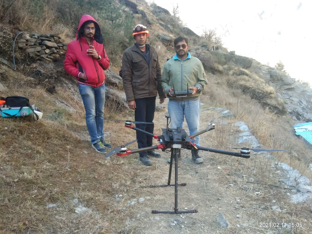 Three men stand outdoors, with one man operating a large drone using a remote controller. The drone is positioned on a stand bearing the Jane logo. The men are dressed in jackets due to cold weather. The date is 2021-02-12, showcasing the practical applications of integrated supply chain management.