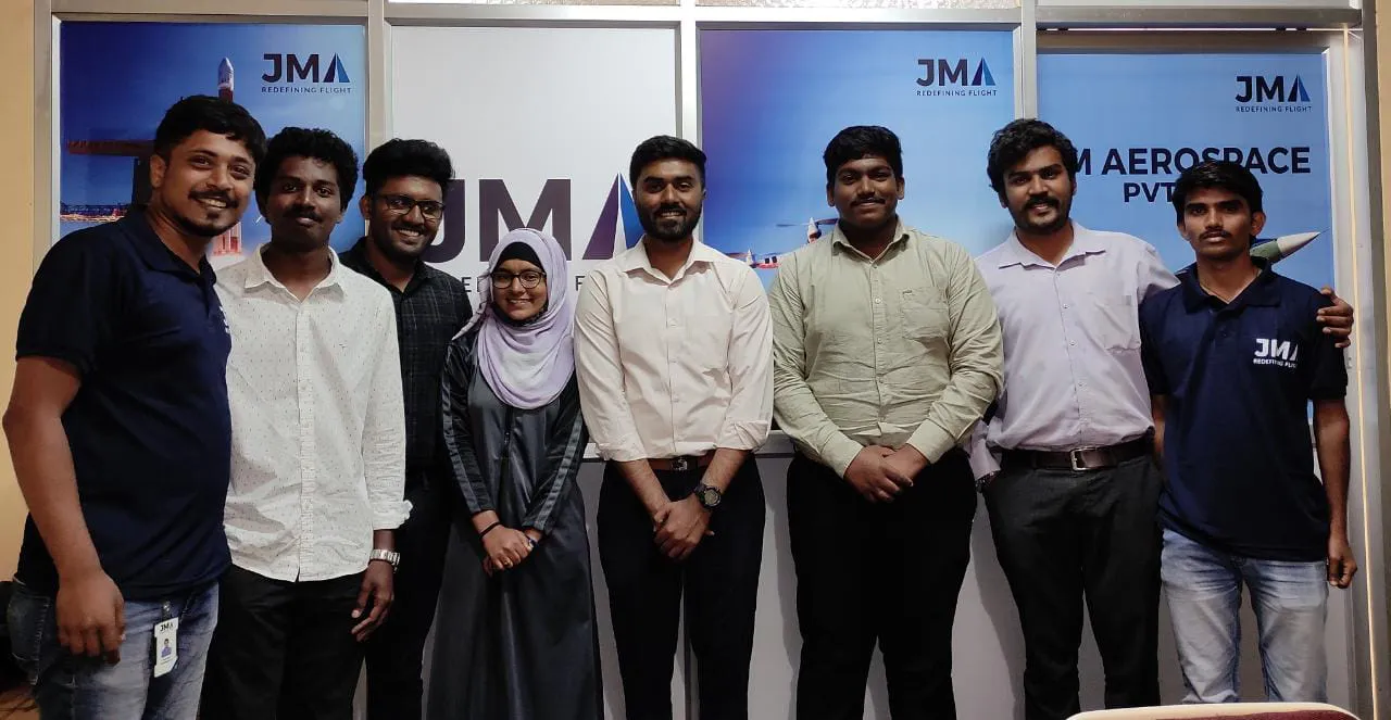 A group of eight people, including men and a woman wearing a headscarf, stand indoors in front of a "Jane Pvt Ltd" backdrop, highlighting their commitment to integrated supply chain management.