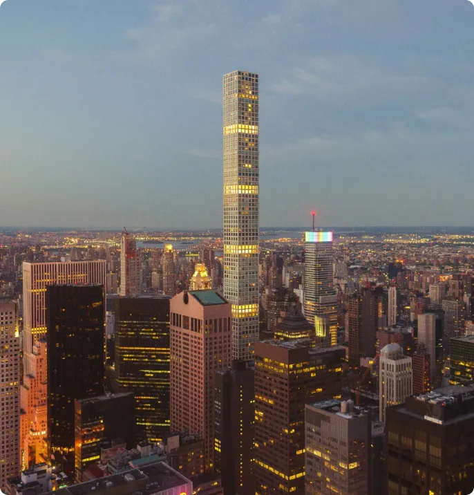 City skyline at dusk featuring a tall, slender skyscraper with illuminated windows, surrounded by other high-rise buildings, highlighting the brilliance of Jane's integrated supply chain management services.